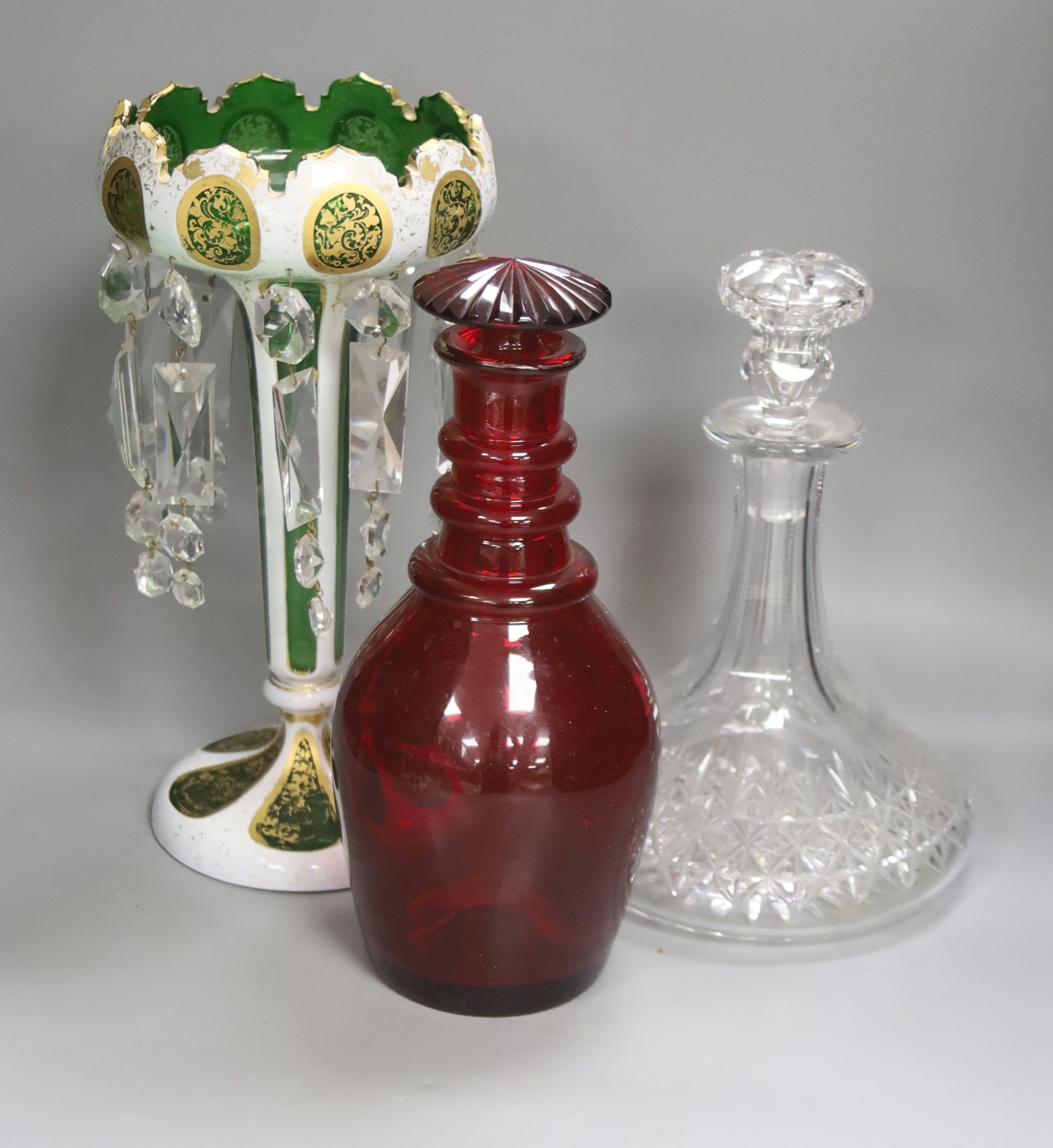 A rare ruby glass decanter circa 1830, a Bohemian overlaid glass table lustre and a cut clear glass ship's decanter, tallest 30cm